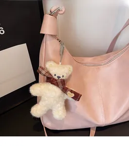 Detailed view of pink leather shoulder bag with a cute teddy bear charm accessory