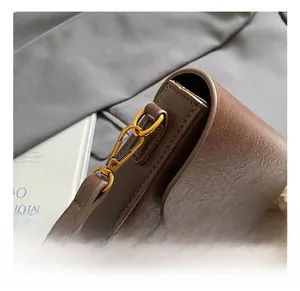 Detailed close-up of premium gold metal hooks on a dark brown lychee texture leather bag