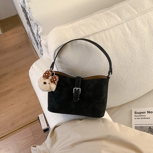 Close-up of black matte leather shoulder bag with silver buckle and plush bear charm