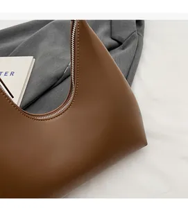 Détail de la texture en cuir synthétique marron lisse et de la fermeture éclair du sac