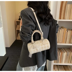 Vue détaillée du petit sac bandoulière cylindrique avec motif damier et nœud en dentelle