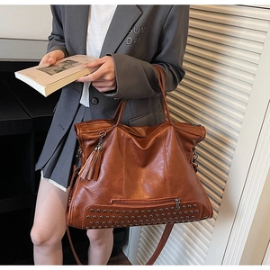 Detail view of retro brown tote bag with silver metal rivets and stylish fringe tassel decoration