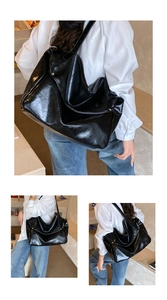 Detail of a large black glossy tote bag showing the soft faux leather texture and strap