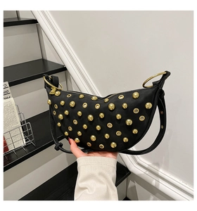 Detail of black crescent shoulder bag with golden studs and metal eyelet decorations