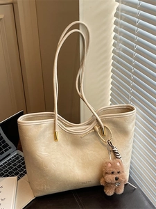 Chic beige tote bag with pleated leather texture and a cute brown plush bear charm