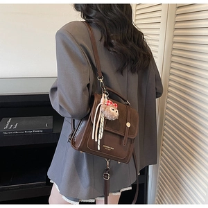 Detail of vintage brown contrast backpack with metal buckle and plush monkey charm