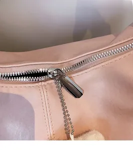 Detailed close-up of smooth silver metal zipper and hardware on a pink leather tote bag