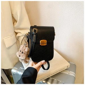 Detailed macro view of black textured leather mini shoulder bag with vintage gold buckle
