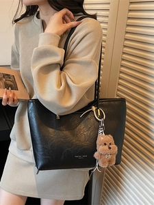Fashionable black faux leather tote bag with a cute bear pendant for elegant women