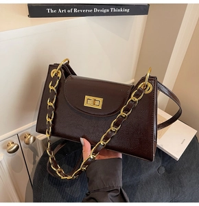 Détail d'un sac à bandoulière en cuir verni marron foncé avec chaîne dorée et fermoir