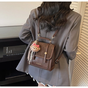 Detailed side view of vintage brown leather backpack with adjustable straps and plush charm