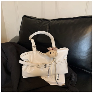 Detail of white glossy patent leather tote bag with silver hardware and bear charm