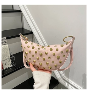 Detailed macro view of pink saddle bag with golden studs and metal eyelet accents
