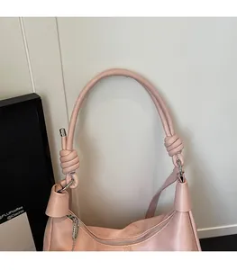 Detail of soft pink tote bag featuring a knotted shoulder strap and silver metal zipper