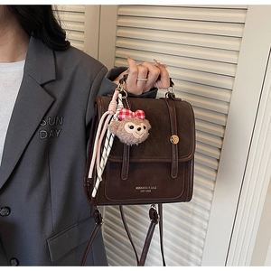 Detail view of brown vintage backpack with leather texture and plush charm accessory