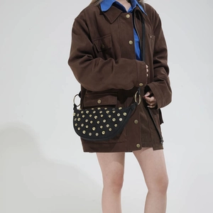 Detail of black half-moon crossbody bag with gold rivets and large metal rings