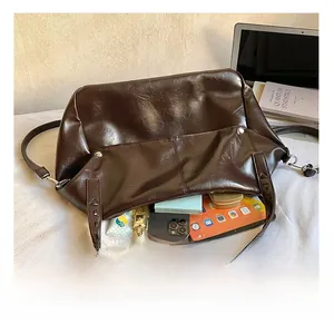 Detail of spacious dark brown tote bag showing interior capacity with tablet and books