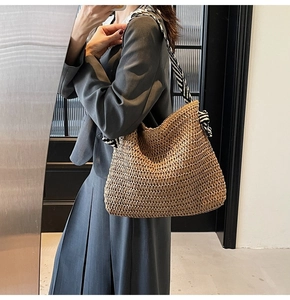 Detail of hand-woven straw tote bag with elegant black and white striped scarf shoulder strap