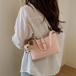 Detail of light pink shoulder bag with leather texture and cute plush bear charm