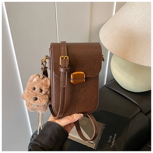 Detail of dark brown crossbody bag with lychee texture and golden clasp