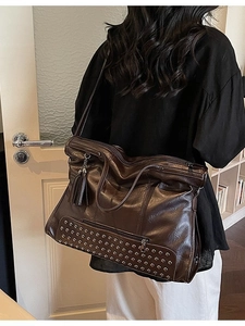 Retro dark brown tote bag with silver studs and tassel worn by a model in casual setting