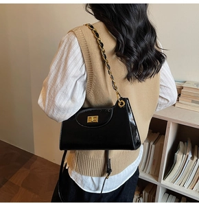 Détail du sac à bandoulière en cuir verni noir avec fermoir doré et bandoulière en chaîne