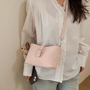 Detail of light pink shoulder bag with PU texture and cute brown teddy bear keychain charm