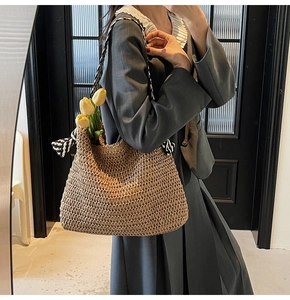 Detail of hand-woven straw tote bag with elegant black and white striped scarf handle