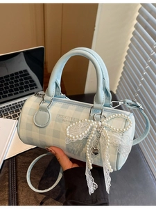 Sac cylindre à damier bleu avec nœud en perles et dentelle dans un décor de bureau