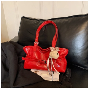 Close-up of bright red patent leather tote bag with stylish buckle and cute bear charm