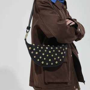 Detail of black suede moon bag with golden studs and metal ring strap link