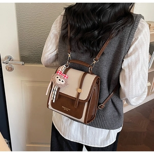 Close-up of retro color-block backpack with cute bear pendant and printed typography