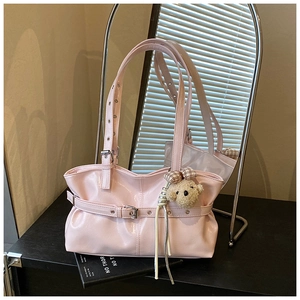 Detail view of pink patent leather tote bag with brown plush bear charm and glossy finish