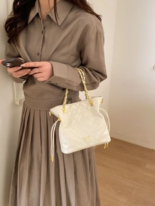 Détail du sac seau matelassé blanc avec bandoulière en chaîne dorée et cordon