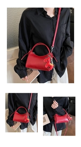 Detalle de bolso de cuero rojo oscuro con colgante de caballo y correa ajustable