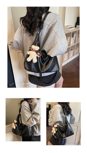 Detail of black leather tote bag with shoulder strap knot and teddy bear charm accessory