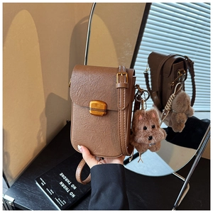 Detailed view of brown textured leather mobile phone bag with golden metal lock and dog charm
