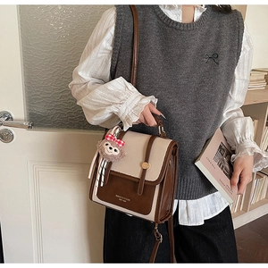 Close-up of vintage brown and beige patchwork crossbody bag with plush doll charm detail