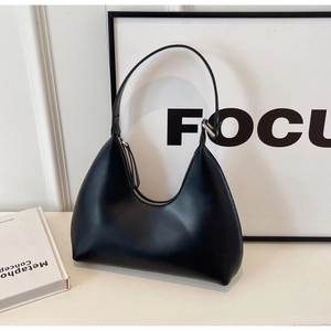 Détail d'un sac hobo noir en forme de croissant avec finition brillante et bandoulière