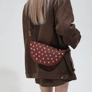 Detail showing Burgundy leather half-moon bag with gold studs on a model's shoulder