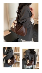Detail of a large dark brown hobo shoulder bag with a cute bear charm on wide strap