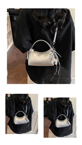 Bolso de mano plateado metalizado con colgante de caballo y borlas llevado por modelo