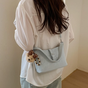 Detail of light blue leather crossbody bag featuring silver buckle and cute bear charm