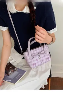 Detail of purple plaid handbag with bow and heart pendant worn by model in casual style