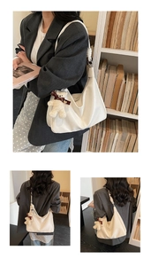 Detail of white leather crescent hobo bag with a cute bear charm and knotted shoulder strap