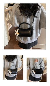 Detalle del bolso negro de media luna con colgante de caballo y correa ajustable