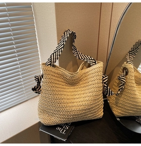 Detail of straw woven tote with black and white striped straps and knot decor