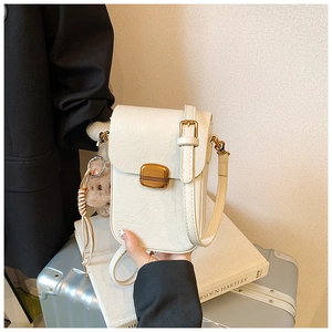 Detail of off-white mini crossbody phone bag with vintage gold buckle and bear charm