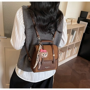 Close-up of retro brown backpack featuring contrast texture, logo detail and plush pendant