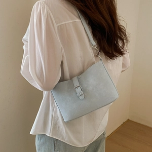 Detail of light blue faux leather shoulder bag with silver buckle and pebbled texture surface